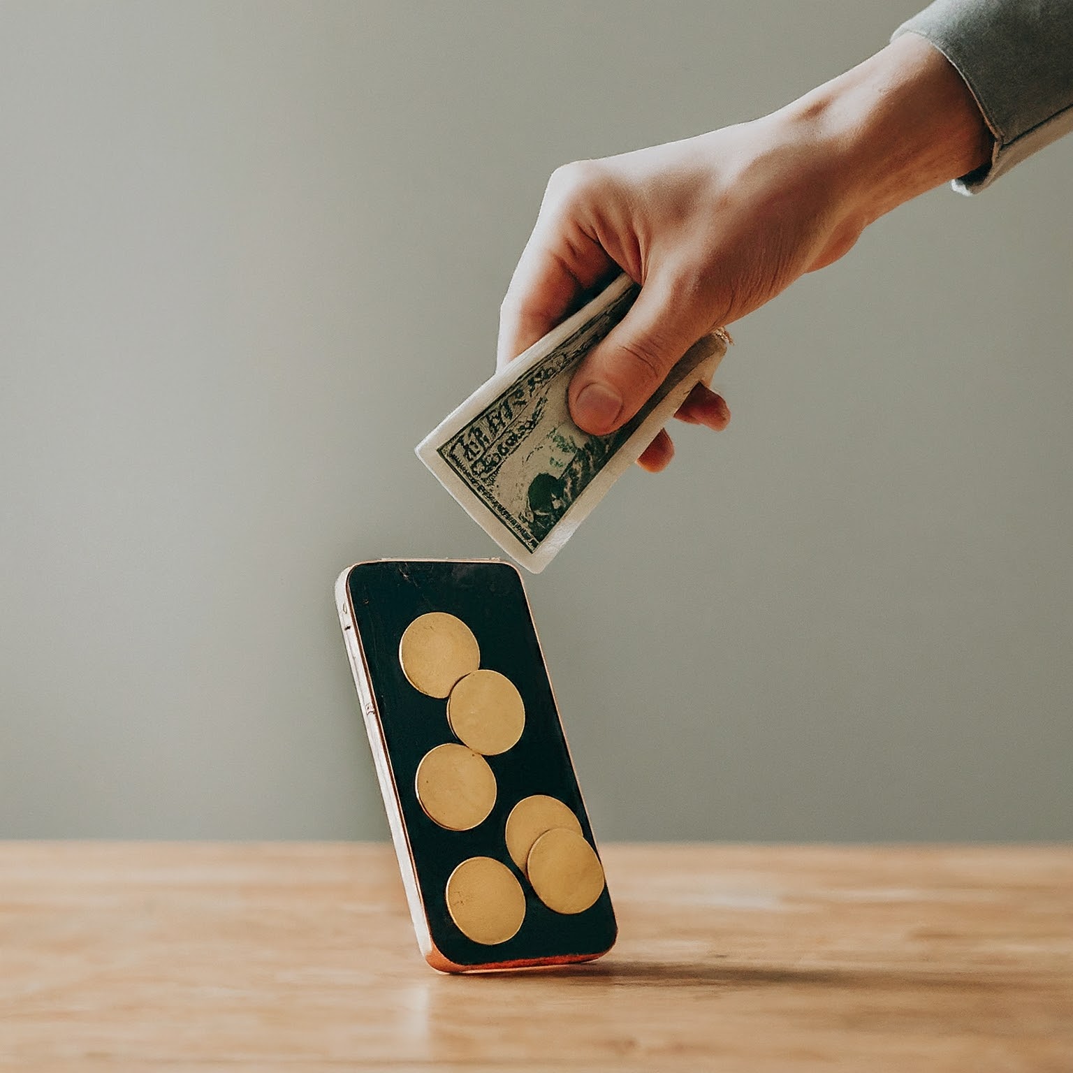 ALT Text: A person pouring money into a smartphone screen, symbolizing wasted ad spend on ineffective social media campaigns